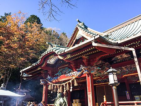 Veduta di una sezione decorata del Tempio Takao-san Yakuo-in sul Monte Takao con una persona di spalle in primo piano.
