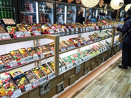 Banco di vendita di bento colorati in una stazione giapponese con un uomo.