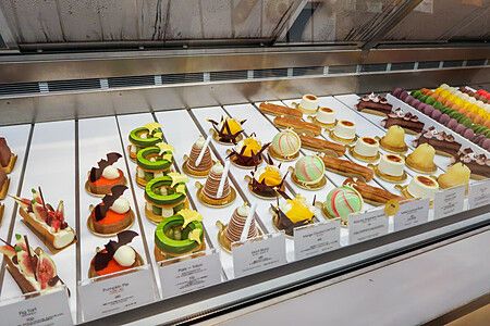 Vetrina di una pasticceria a Tokyo con file di dolci monoporzione, éclair e macarons disposti su vassoi bianchi.