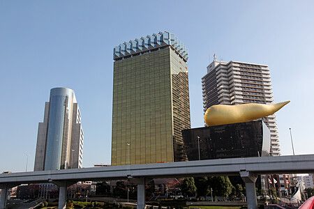 Asahi Beer Hall ad Asakusa, Tokyo, con fiamma dorata e grattacieli sullo sfondo.