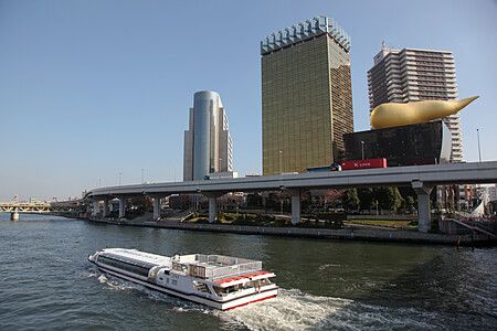 Asahi Beer Hall a Tokyo con una barca sul fiume Sumida.