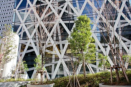 Dettaglio della facciata della Cocoon Tower a Shinjuku con alberi