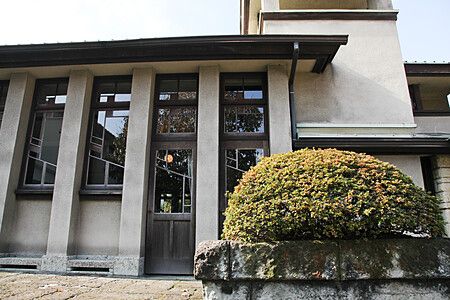 Edificio del Jiyugakuen Myonichikan con arbusto in primo piano.