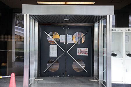 Ingresso della Nakagin Capsule Tower con porta geometrica in metallo.
