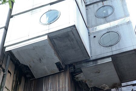 Porzione della Nakagin Capsule Tower a Tokyo con moduli abitativi cubici e oblò.