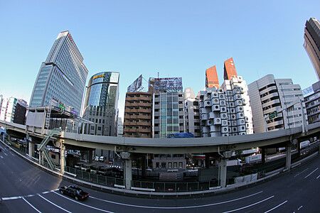 Veduta della Nakagin Capsule Tower circondata da moderni edifici a Tokyo.