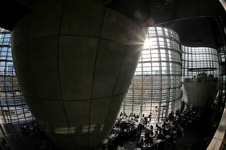 Interno del The National Art Center a Tokyo con ampie vetrate e persone ai tavoli.