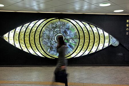 Persona cammina davanti a "The Eye of Shinjuku" alla stazione di Shinjuku.