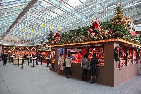 Mercatino natalizio a Roppongi Hills, Tokyo, con persone che osservano bancarelle decorate.