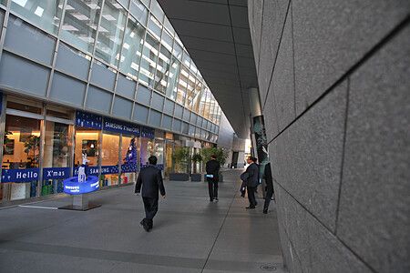 Persone camminano in un corridoio a Roppongi Hills con vetrate e decorazioni natalizie.