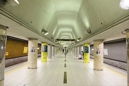 Interno della Stazione di Iidabashi a Tokyo con corridoio moderno e colonne.
