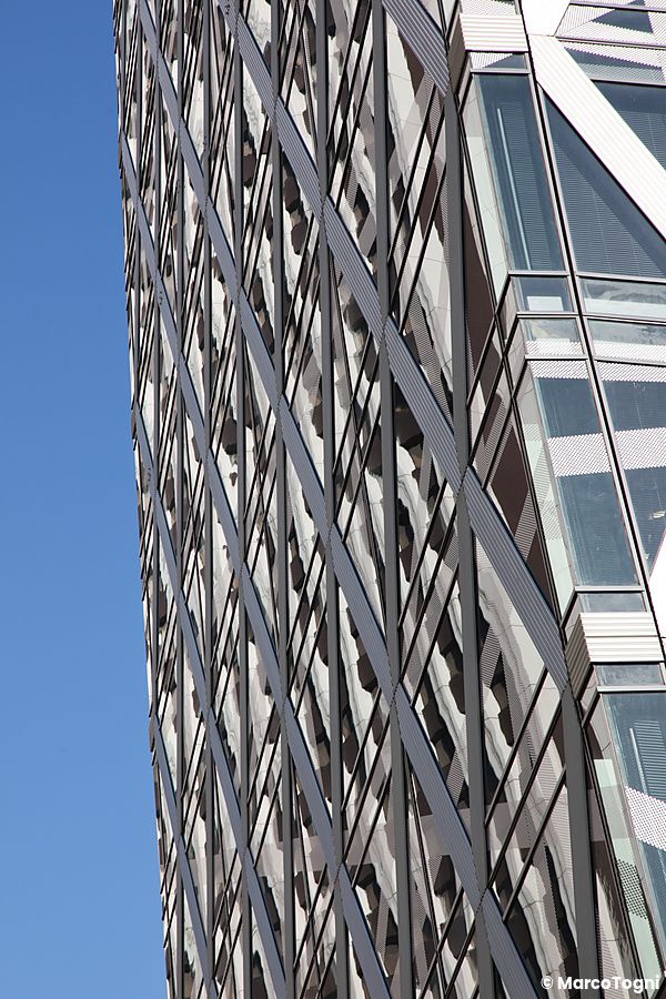 Facciata geometrica della Cocoon Tower a Shinjuku contro il cielo blu.