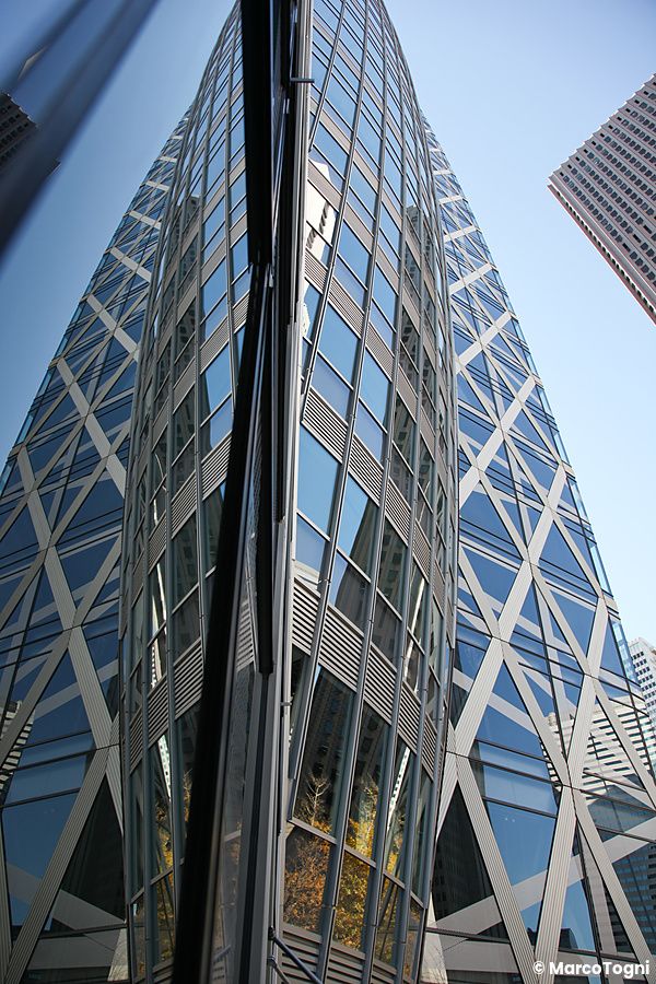 Vista ravvicinata della Cocoon Tower a Shinjuku, Tokyo, con riflessi sulla facciata.