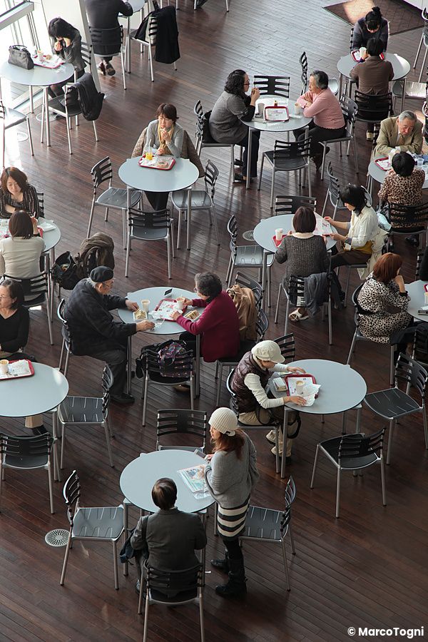 Persone sedute a tavoli tondi all'interno di The National Art Center.