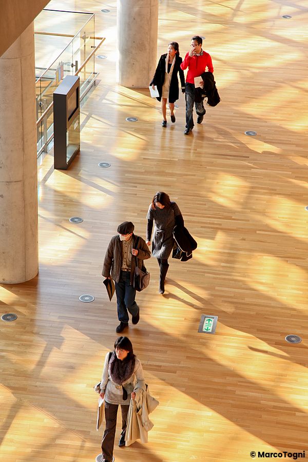 Persone camminano all'interno di The National Art Center a Tokyo con luce naturale.