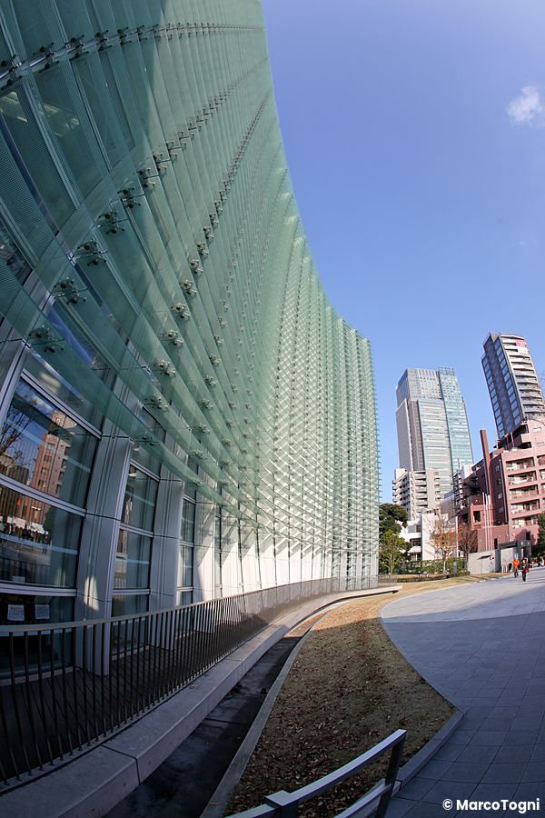 Facciata di vetro di The National Art Center a Tokyo con grattacieli sullo sfondo.