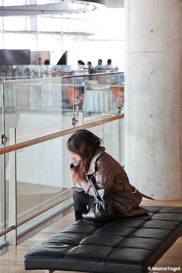 Persona seduta su una panca all'interno di un museo moderno a Tokyo.