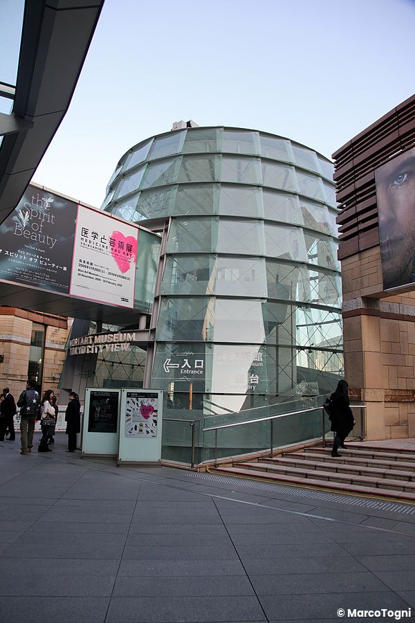 Torre di vetro moderna nel complesso roppongi hills a tokyo con persone vicino