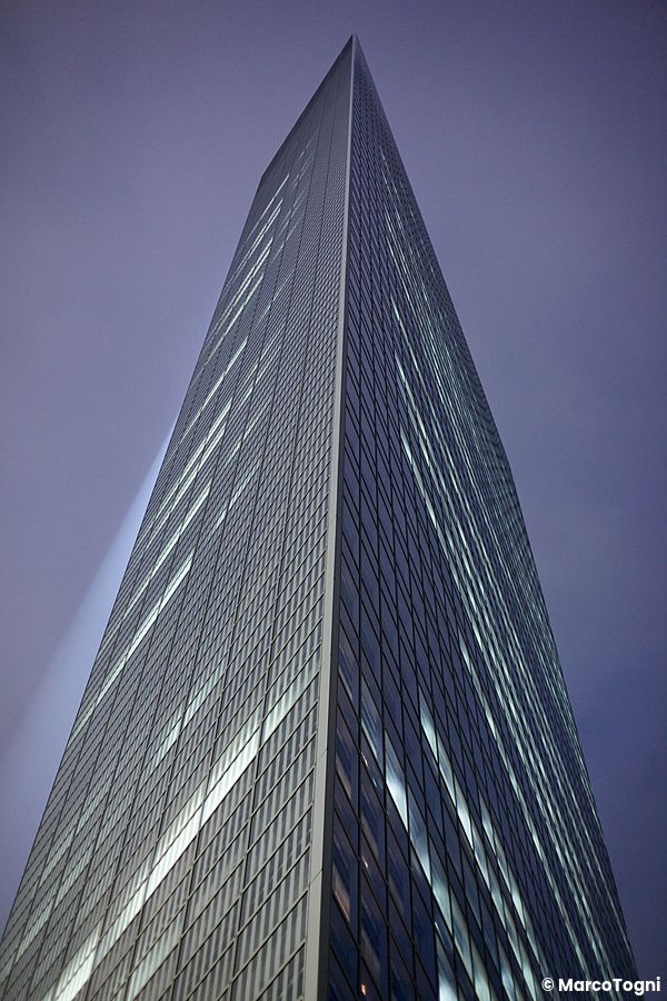 Un grattacielo illuminato nel quartiere di Shiodome, Tokyo, visto dal basso verso l'alto.