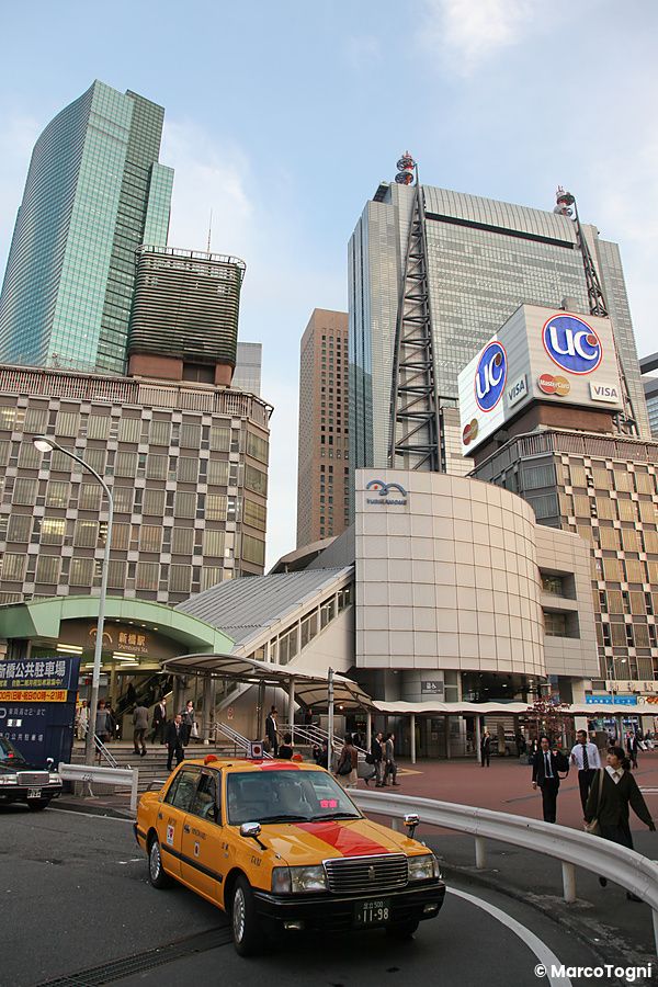 Taxi giallo su strada trafficata con moderni grattacieli a Shiodome, Tokyo.