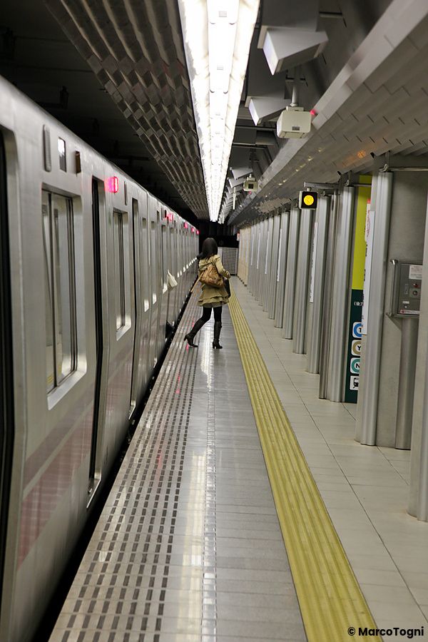 Persona sulla piattaforma della stazione di Iidabashi a Tokyo accanto a un treno fermo.