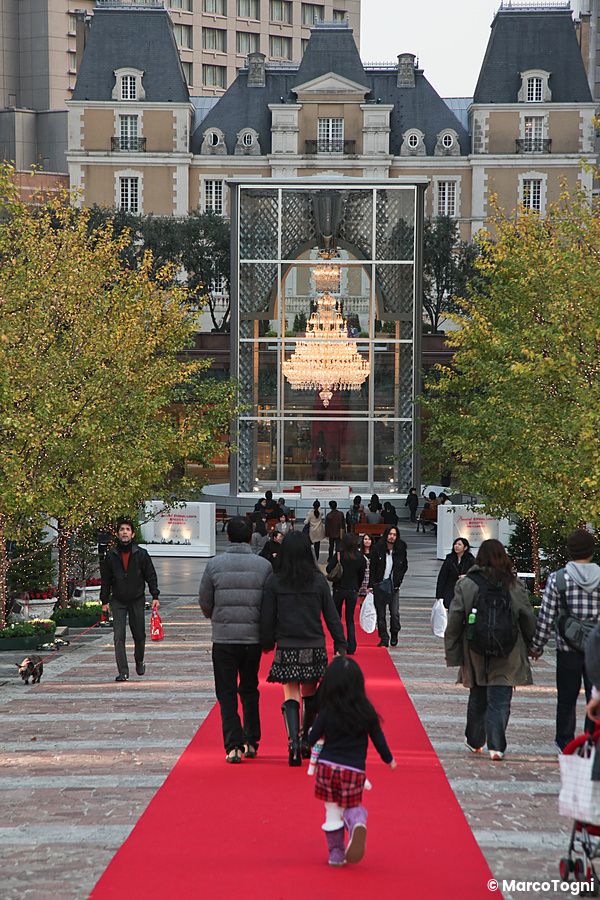 Persone camminano sul tappeto rosso lungo il corridoio che dalla stazione di Ebisu porta a Yebisu Garden Place.