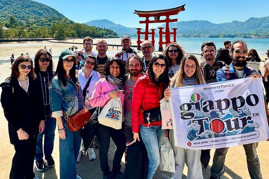 Gruppo di viaggiatori durante GiappoTour Reiwa, sull'isola di Miyajima con il torii sullo sfondo.