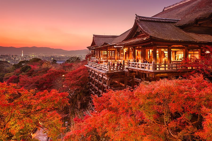 Tempio Kiyomizu-dera di Kyoto al tramonto con foglie autunnali rosse.