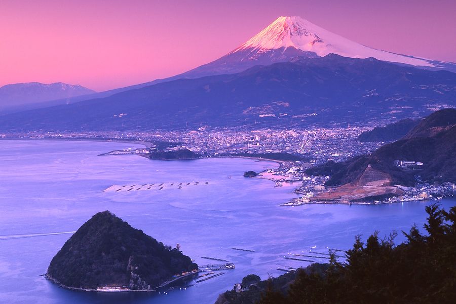 Monte Fuji di notte con la baia di Suruga in primo piano.