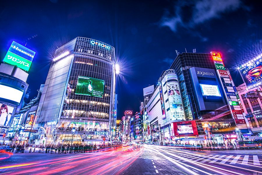 Incrocio di Shibuya a Tokyo di notte, tra luci e cartelloni pubblicitari.