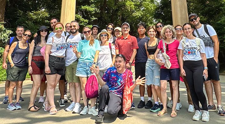 Un gruppo di viaggiatori, con Marco Togni al centro, e parzialmente visibile il torii di ingresso del santuario Meiji Jingu.