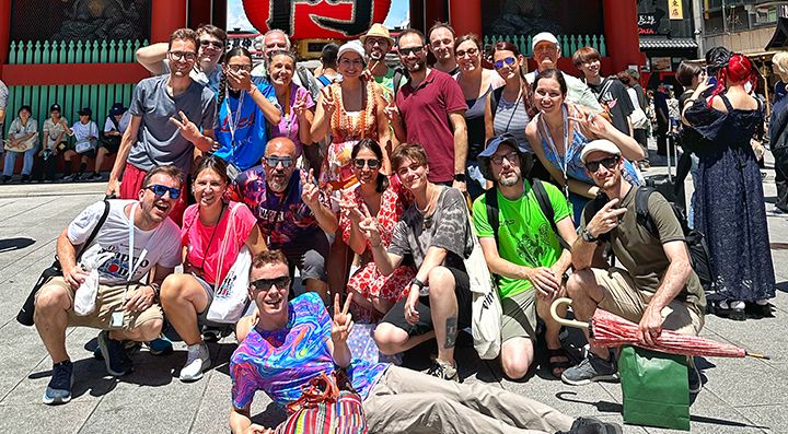 Un gruppo di viaggiatori davanti ad una porta tradizionale in un tempio in Giappone, e Marco Togni sdraiato per terra.