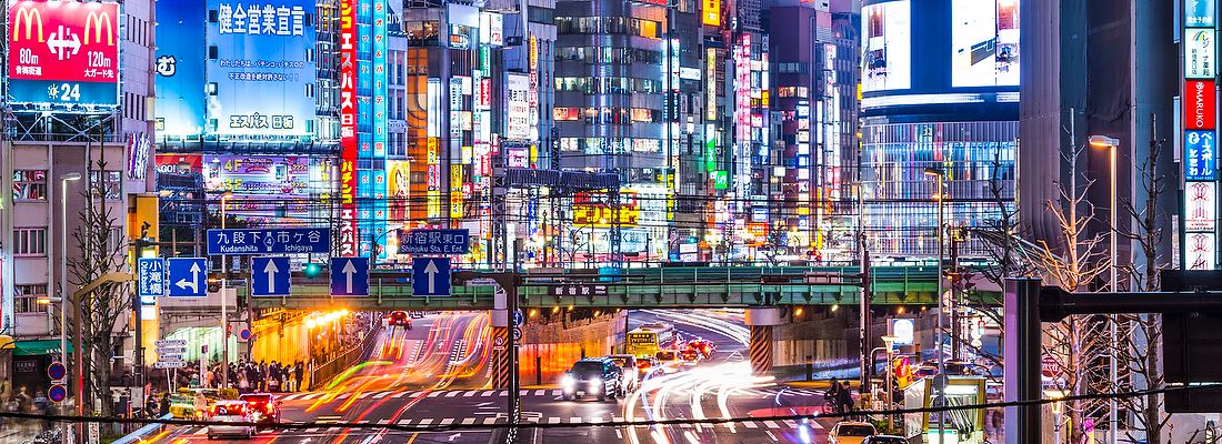 Shinjuku illuminato di notte con traffico e insegne al neon.