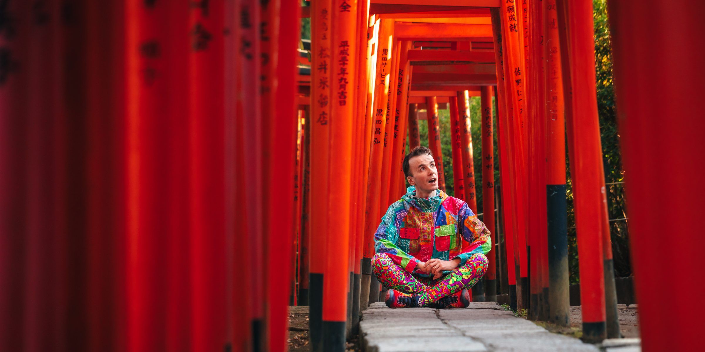 Marco Togni seduto in mezzo a un tunnel di torii rossi in Giappone