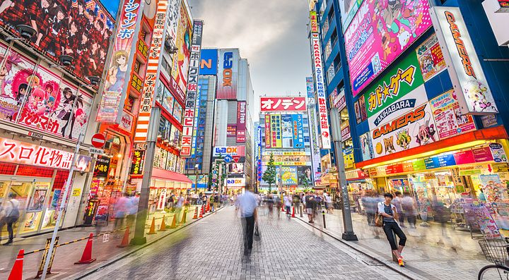 Street di Akihabara a Tokyo, con insegne colorate e folla in movimento.