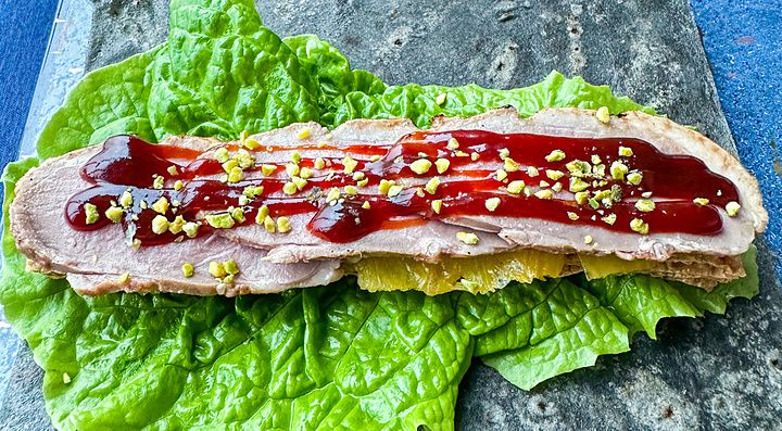 Anatra laccata a fette con salsa a China Blue a Tokyo servita su una foglia di lattuga e una base di pietra scura.