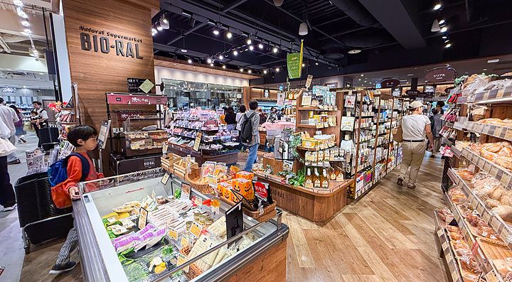 Interno del supermercato Bio-Ral con scaffalature in legno e clienti tra le corsie di prodotti biologici.