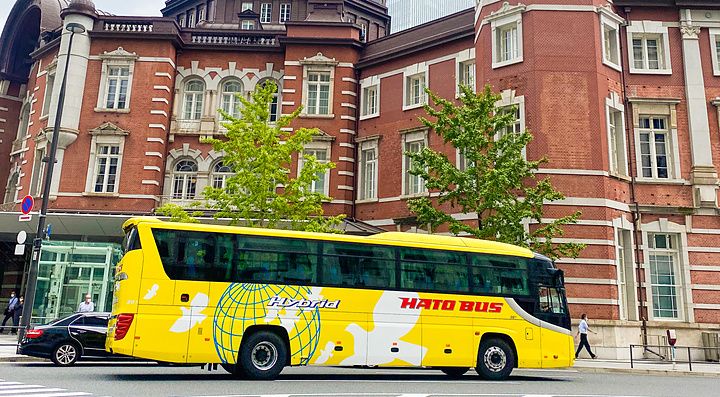 Un bus turistico Hato no Bus giallo davanti alla stazione di Tokyo nel quartiere Marunouchi.