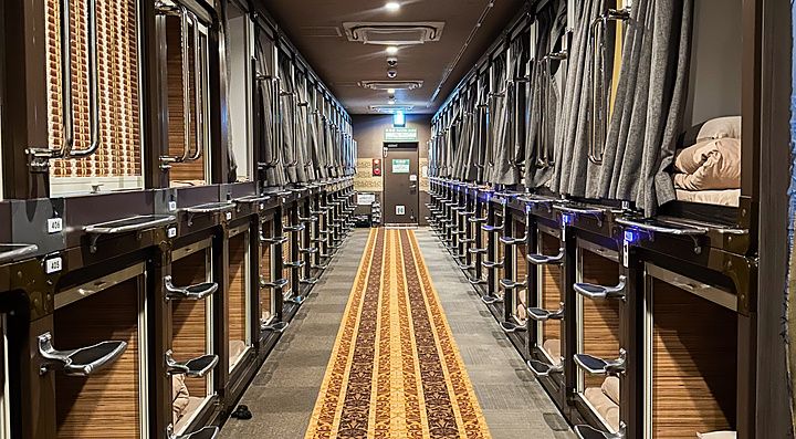 Corridoio di un capsule hotel con capsule su entrambi i lati.