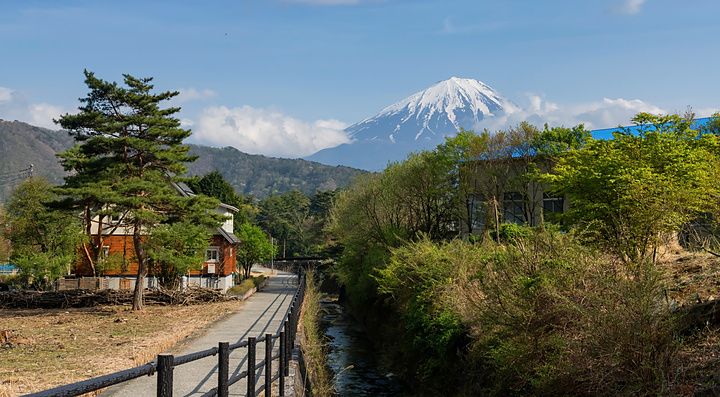 Casa tradizionale giapponese vicino a un canale con vista sul monte Fuji innevato in una giornata di primavera.