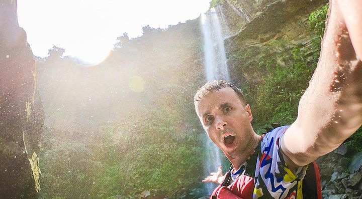 Marco Togni con giubbotto di salvataggio rosso scatta un selfie davanti alle Cascate di Pinaisara sull'Isola Iriomote.