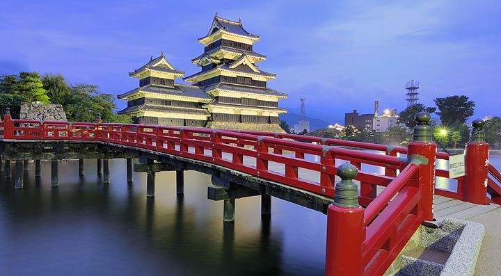 Castello di Matsumoto al crepuscolo con ponte rosso e cielo blu.