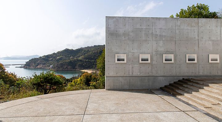 Parete in cemento a vista con quadri incassati su un piazzale che affaccia sul Mare interno di Seto, in Giappone.