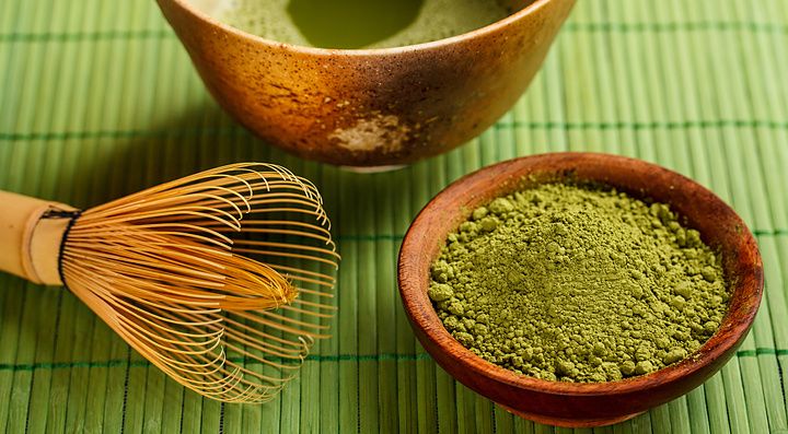 Ciotola di matcha e strumenti per la cerimonia del tè giapponese su tovaglietta verde.