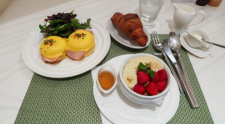 Una colazione con uova alla Benedict e una ciotola di frutta e cereali su un tavolo del ristorante Sarabeth a Tokyo.