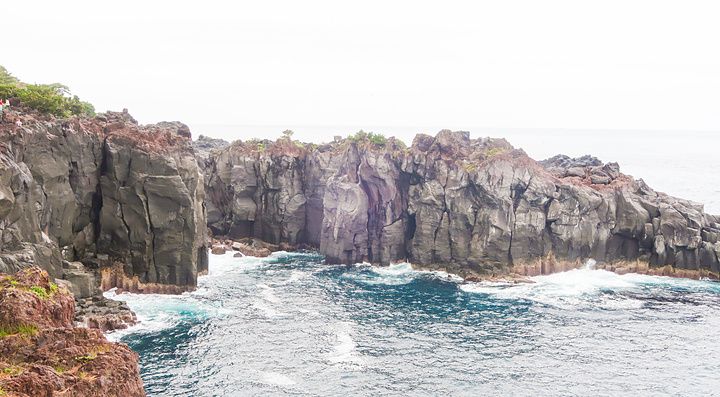 Scogliere di roccia vulcanica scura si affacciano sull'oceano presso la Costa di Jogasaki (Giappone).