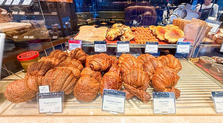 Vetrina colma di vari tipi di croissant e prodotti da forno all'interno di The City Bakery a Shibuya.