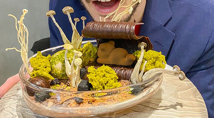 Marco Togni con occhiali rosa guarda un dolce con funghi servito in un piatto di vetro presso Le Musée a Ginza.
