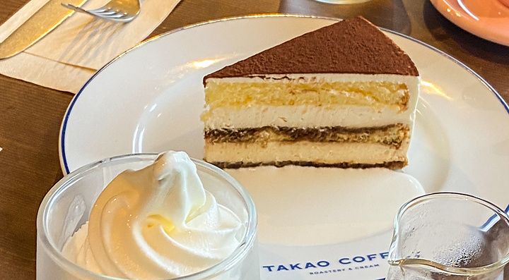 Una fetta di tiramisù, un gelato soft e un contenitore con caffè su un tavolo presso Takao Coffee.