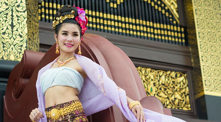 Donna thailandese in abito tradizionale con sfondo dorato.